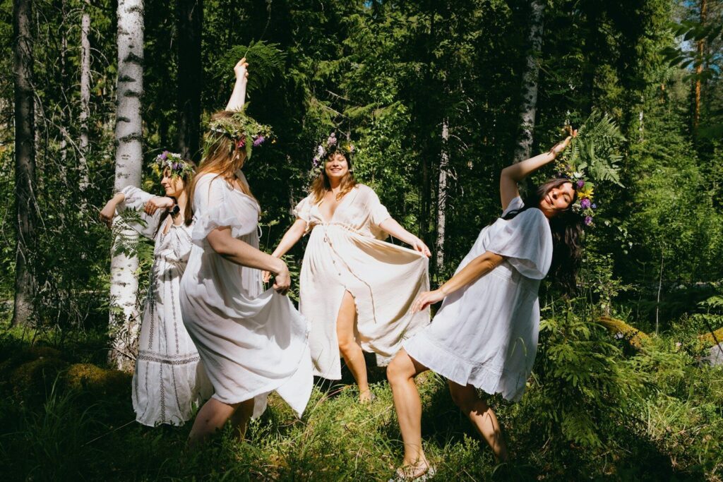 Gruppe von Frauen im weißen Kleid tanzt durch den Wald