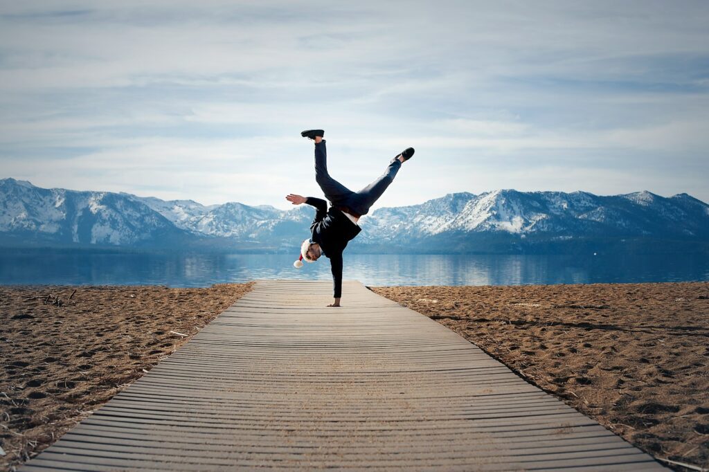 Handstand auf einer Hand vor Berg und Seekulisse