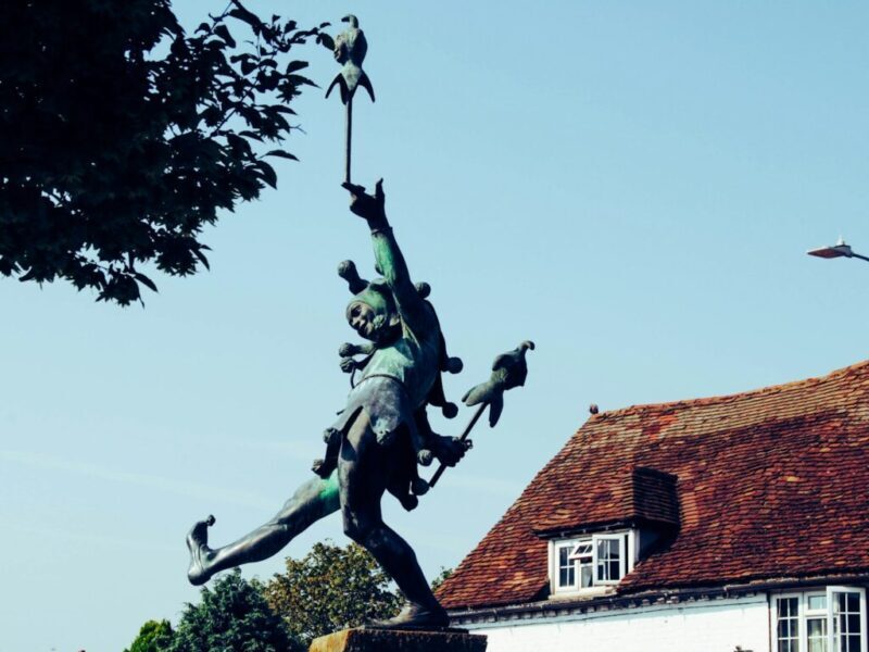 woman with birds statue near house during daytime